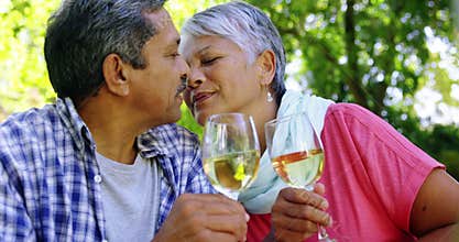 Senior couple kissing while drinking wine