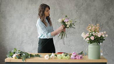 People, business, sale and floristry concept - happy smiling florist woman making bunch at flower shop, bouquet with