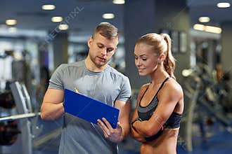 Smiling young woman with personal trainer in gym