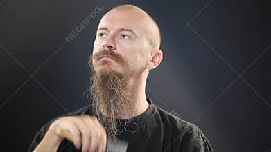 Bald man with long beard brashing his beard