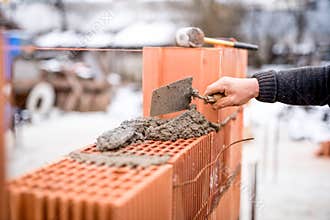 Construction site with worker building brick walls with mortar and bricks