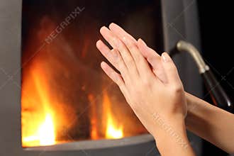 Woman hands heating in front a fire place