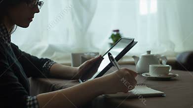 Business woman using a tablet and notebook in cafe