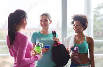 Happy women with bottles of water in gym