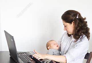 Modern mother holding baby while working in office