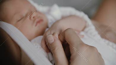 Newborn baby hand holding adult finger