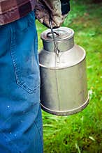 Farmer carrying a vintage dairy milk can.