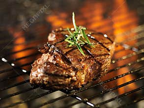 Steak cooking over flaming grill
