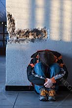 Boy teens sitting on the floor alone in city. 