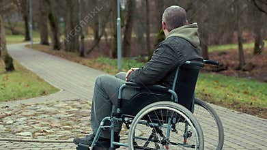 Disabled man in wheelchair waiting for assistance on path in the park