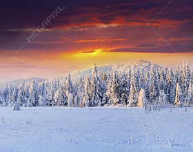 Dramatic winter sunset in snowy mountains.