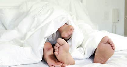 Young couple under duvet in their bed