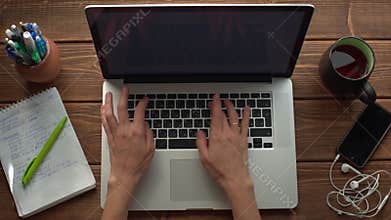 Woman working with laptop placed on wooden desk