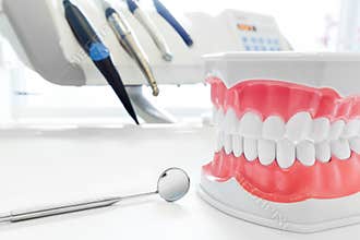 Clean teeth dental jaw model, mirror and dentistry instruments in dentist's office.