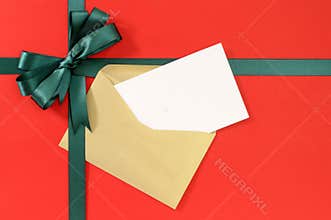 Open Christmas or birthday card, green gift ribbon bow on plain red paper background