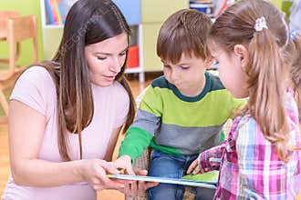 Teacher Showing a Book to Children at the Nurcery