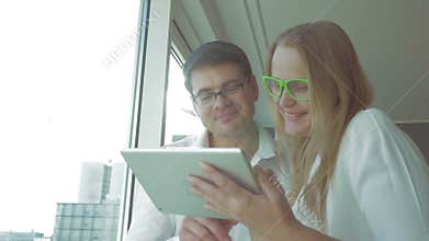 Happy businesspeople using pad by the window