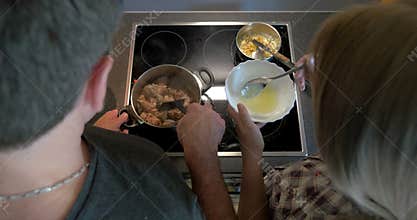 Couple cooking together meat and sauce