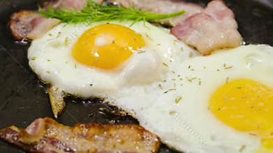 Eggs and bacon, with herbs frying in a pan.