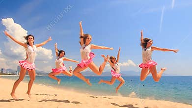Cheerleaders dance squat show poses on beach against sea