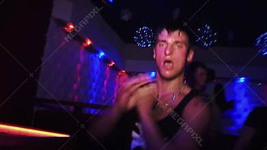 Sweaty guy in a t-shirt dancing in a nightclub at