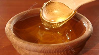 Taking honey by using spoon in wooden bowl, slow
