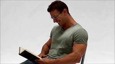 Attractive young man reading book laughing amused by what he sees