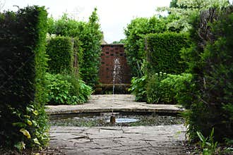 Water Fountain in Pond and Old Flagstone Surrounding Path, Tintinhull Garden, Somerset, England, UK