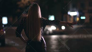 Charming girl hitchhiking on town street at night
