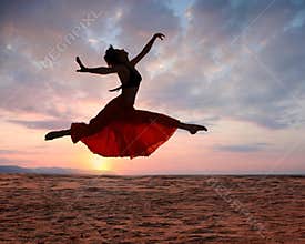 Jumping woman at sunset