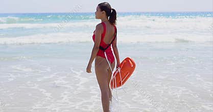 Female lifeguard steps into water on summer day