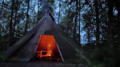 Cooking roasted meat in a Cozy tipi in the dark scandinavian forest