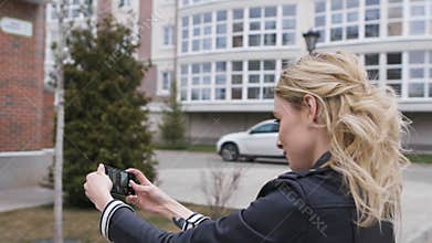 Side portrait of a beautiful blond girl using a smart phone to network, taking selfies pictures in a suburban home