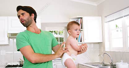 Father grimacing because of need to change baby's nappy