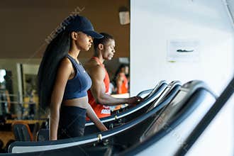 Black trainer and african american woman on the treadmill in gym. Fitness concept