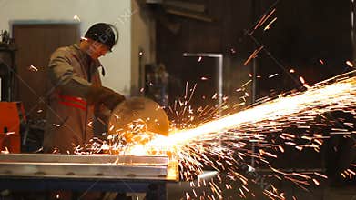 Manual worker in steel factory circular blade on piece of metal. Dolly shot