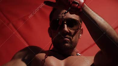 Muscular body of a stripper. Handcuffs and a blade sliding on a naked torso.