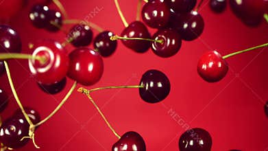 Close-up of cherry flies through the air and rotates a red background
