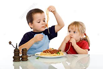 Two kids eating pasta with their hands