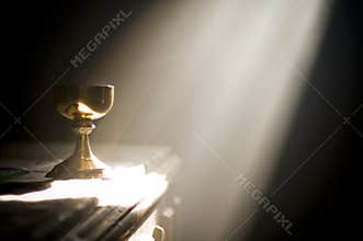 Gold chalice in altar with a ray of divine light