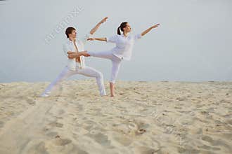 Beautiful athletic couple workout dance on the beach