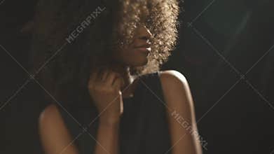 Beautiful exotic shy young black woman covers face by hand and flirting