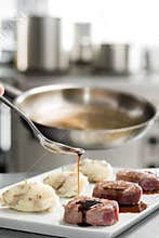 Chef add sause to a beef steaks, light one