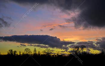 Dramatic and moody multi colors of setting sun and clouds