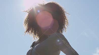 Young afro american woman relaxing in park with a sunset behind her.