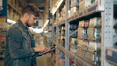 Manager With Tablet PC Checking Goods At Supermarket Warehouse