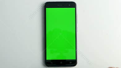 Pressing smart phone with green screen on white