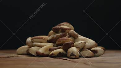 Pile of brazil nuts on a wooden table isolated on black