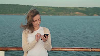Woman using mobile phone on deck of cruise ship