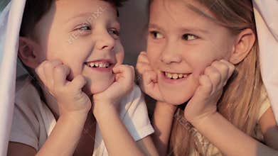 Lovely brother and sister lying in bed at home.